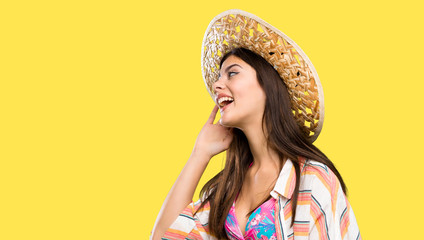 Teenager girl on summer vacation listening to something by putting hand on the ear over isolated yellow background