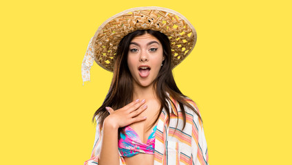 Teenager girl on summer vacation surprised and shocked while looking right over isolated yellow...