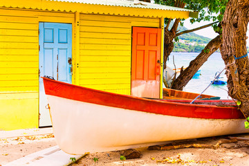 Fototapeta na wymiar Beautiful bright colored wooden house on sea side with colorful wooden boat in front.
