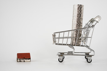 Wood house model on white background   and row of coin money in shopping cart  . Real Estate market, Trading Estate, Mortgage Concepts.