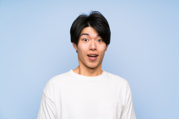 Asian man on isolated blue background with surprise facial expression
