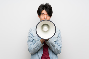 Asian man on isolated white background shouting through a megaphone