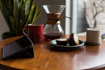 A modern living room coffee table with a coffee cup, book, tablet, and a muffin on it.