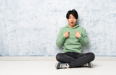 Asian man sitting on the floor with surprise facial expression