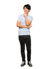 A full-length shot of a Asian man with blue shirt looking to the side over isolated white background