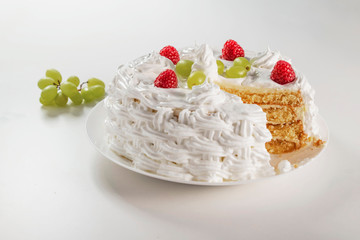 Creamy homemade cake made from natural ingredients with raspberries and grapes on a white background.
