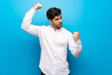 Young man over isolated blue wall celebrating a victory