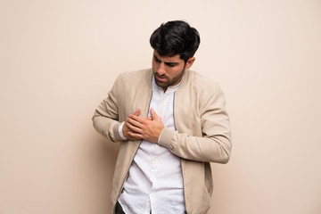 Young man over isolated wall having a pain in the heart