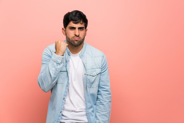 Fototapeta premium Young man over pink wall with angry gesture