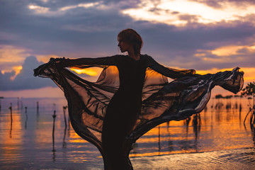 young woman standing in water at sunset silhouette
