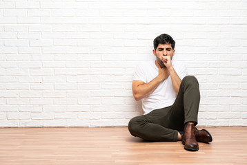 Young man sitting on the floor is suffering with cough and feeling bad
