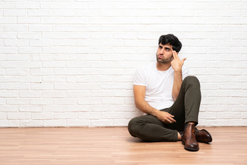 Young man sitting on the floor with problems making suicide gesture