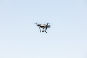 Landing a droned hand with spinning propellers. Flying drone on blue sky.