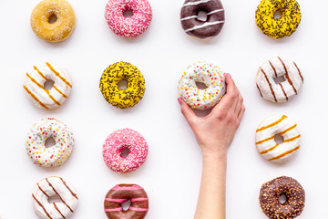 Modern design with bright donuts in hand on white background top view pattern