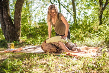 Girl masseuse provides a thorough massage  on the forest floor.