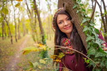 Beautiful girl smiling at the camera, in stylish autumn fashion clothes, in a park scenery. Gorgeous romantic young woman outdoors. Landscape close-up shot in natural light, retouched, vibrant colors