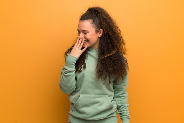 Teenager girl over ocher wall smiling a lot