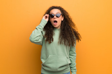 Naklejka premium Teenager girl over ocher wall with glasses and surprised