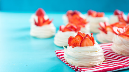 Beautiful pavlova cakes with strawberries on a blue background. Selective focus. Tasty sweet breackfast. Wedding morning. Meringue with cream.