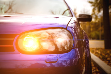 Fototapeta premium Modified yellow xenon headlights of blue modern car. Lowrider with air suspension Parked in the park