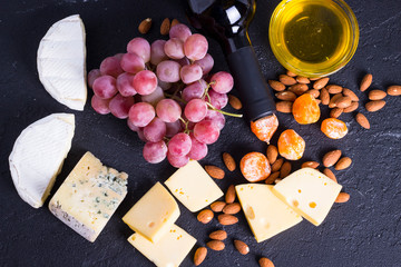 Snacks with wine - bottle, various types of cheeses, figs, nuts, honey, grapes