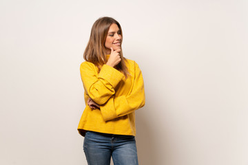 Woman with yellow sweater over isolated wall looking to the side