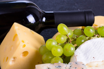 Snacks with wine - bottle, various types of cheeses, figs, nuts, honey, grapes