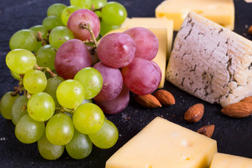Snacks with wine - various types of cheeses, figs, nuts, honey, grapes