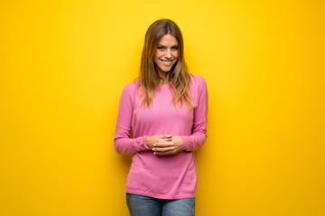 Obraz premium Woman with pink sweater over yellow wall laughing looking to the front