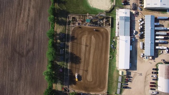 Aerial of water truck wetting down the dirt area in an effort to keep down the dust as horses and riders workout just feet away, Kansas, Missouri. Concept: rural,horses,farm machines
