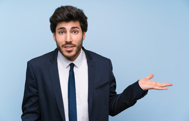 Businessman over isolated blue wall making doubts gesture