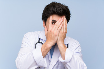 Doctor man covering eyes and looking through fingers