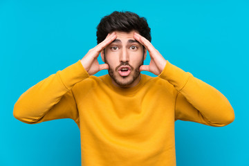 Handsome over isolated blue wall with surprise expression