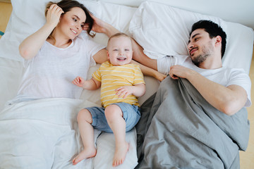 Young family resting together in parent's bed in the morning