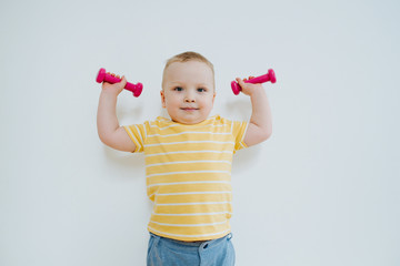 Portrait of little baby going to play with dumbbells