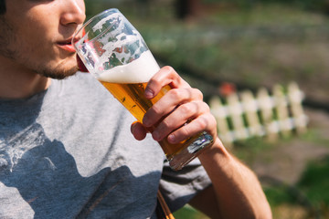 A man drinks beer from a glass lying on a hammock