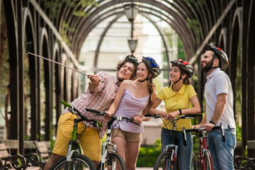 Obraz na płótnie Canvas Young people taking selfie outdoors. Friends having fun together in summer park. Summer tour by bikes.