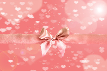 Pink ribbon with decorative bow on colorful light background. Festive background.