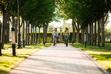 Fototapeta premium Young people cycling on road in park. Tourists on summer vacation. People and summer rest.