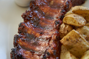 Close-up of grilled pork ribs with baked potatoes.