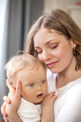 Beautiful mother and little son 9 months in the home interior. Cozy. Baby. Motherhood.