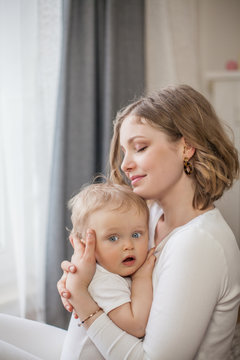 Beautiful mother and little son 9 months in the home interior. Cozy. Baby. Motherhood.