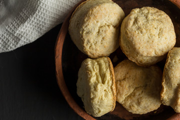Biscuits made with buttermilk - scones in earthenware plate close up on black background