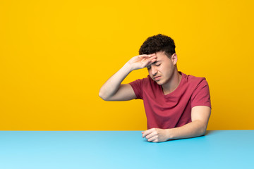 Young man with colorful wall and table with tired and sick expression