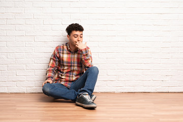 Obraz na płótnie Canvas Young man sitting on the floor having doubts