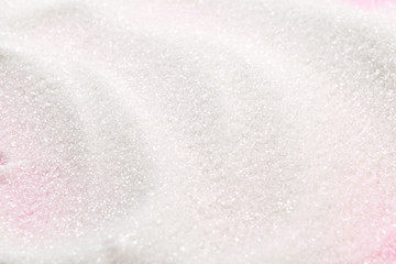 White sugar on a pink background top view