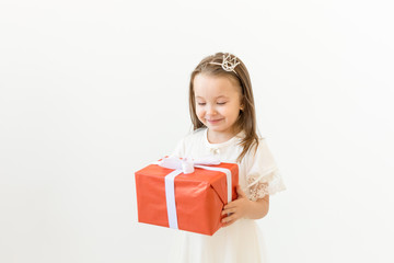 Childhood, children and holiday concept - little girl in white dress with gift box on white background