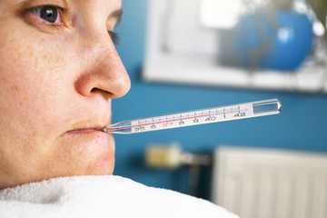 Close up of ill woman with flu and thermometer in her mouth measuring body temperature reaching 40...