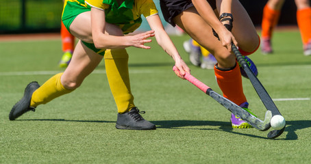 Two women battle for control of ball during field hockey game