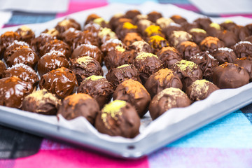 Group of sweet and tasty homemade chocolate balls on a backing paper sprinkled with different spice flavors close up